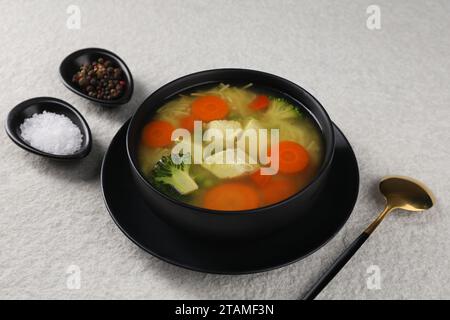 Gustosa zuppa di pollo con spaghetti e verdure in ciotola servita su un tavolo leggermente ruvido Foto Stock