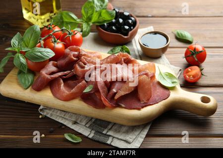 Imbarco con deliziosa bresaola servita con altri spuntini su un tavolo di legno Foto Stock