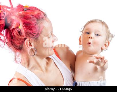 Una giovane madre con dei dreadlocks sta tenendo suo figlio con un'espressione divertente sul suo viso Foto Stock