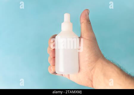 La mano di un uomo bianco che tiene una medicina in una bottiglia bianca con un'etichetta vuota. spazio di copia per la progettazione e il testo Foto Stock