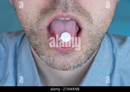 Un giovane che prende medicine per alleviare il dolore. Primo piano su un tablet bianco Foto Stock