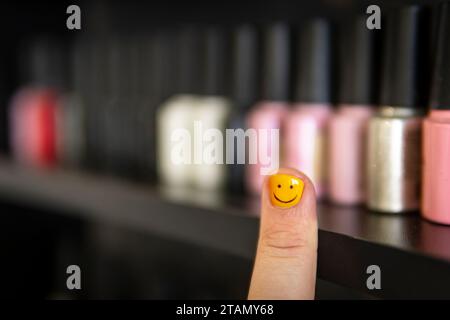 Un uomo con unghie dipinte. Design chiodi maschili. uomini manicure. Scelta dello smalto per unghie in un negozio di cosmetici. numerose opzioni di smalto per unghie sul ripiano in t Foto Stock