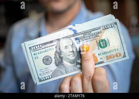 dollari in mano. Uomo d'affari in camicia blu che regge 500 dollari. un fan dei soldi. Manicure per uomini sulla mano. Il concetto della gioia dello stipendio e' Foto Stock