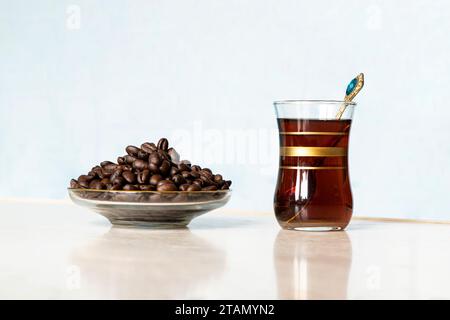 Una tazza di vetro nel tradizionale stile turco con banchi di caffè neri con chicchi di caffè sdraiati sul tavolo. Una deliziosa bevanda energetica. Foto Stock