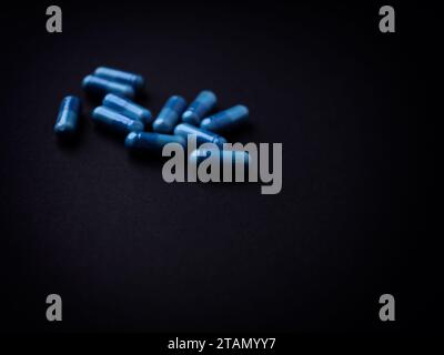 Capsule di aminoacidi su sfondo di carta scura. Messa a fuoco morbida. Primo piano. Copia spazio. Foto Stock