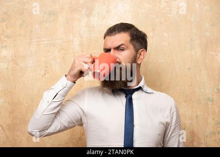 Buon giorno. Mans beve una tazza di caffè. Tè del mattino. Buon giorno. L'uomo beve tè. Uomo hipster con una tazza di caffè. L'uomo barbuto tiene il tè della tazza, bevendo Foto Stock