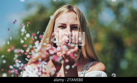 Una ragazza fa saltare un corietto di carta multicolore dalle sue mani. Foto Stock