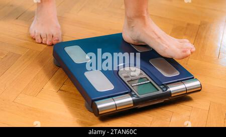 Donna che misura la composizione corporea con scale digitali Foto Stock