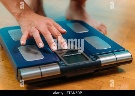 Donna che usa scale di composizione corporea Foto Stock