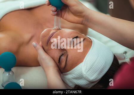 Terapia di coppettazione del viso Foto Stock