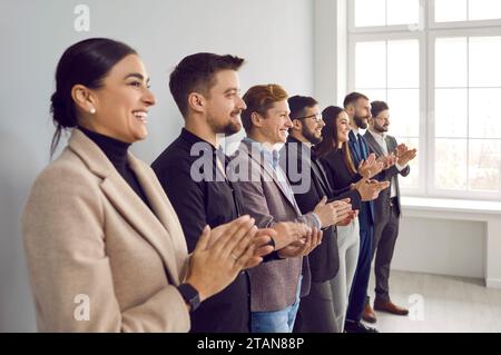 Felici uomini d'affari che applaudono dopo una riunione di gruppo di successo Foto Stock