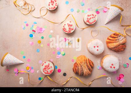 Berliner, panini alla cannella e cupcake per il carnevale e la festa. Krapfen tedesco o ciambelle con rastrellieri e coriandoli. Coloratissimo carnevale o compleanno Foto Stock