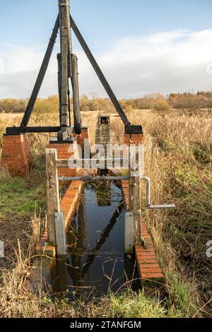 Pompa di drenaggio vecchia, in disuso e abbandonata sulla riva del fiume Foto Stock