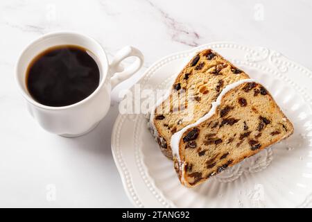 Stollen e caffè caldo su un tavolo. Tazza di caffè caldo e due fette di tradizionale pane tedesco natalizio di noci, spezie e frutta secca su un piatto. Foto Stock