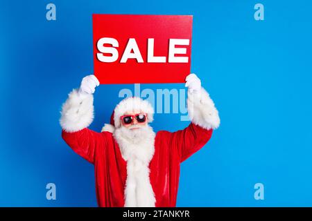 Ritratto fotografico di uomo pensionato maturo aumentare la vendita di piante vestito elegante costume di babbo natale isolato su sfondo blu Foto Stock
