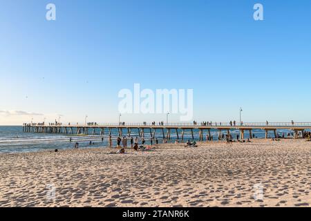 Adelaide, Australia meridionale - 2 gennaio 2023: Glenelg Beach brilla di luce mentre la gente si gode il sole sulle sabbie dorate con il molo visto sullo sfondo Foto Stock