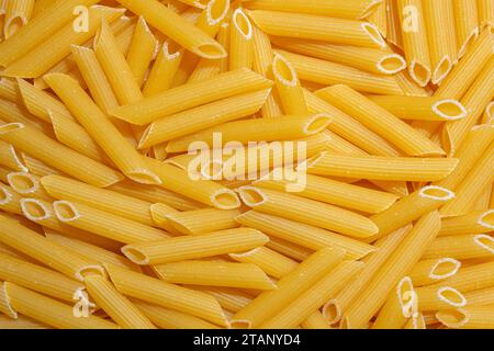 Penne rigate Pasta crude: Una tela culinaria di penne Macaroni, che crea uno sfondo vivace e testurizzato per una cucina gourmet. Pasta secca. Raw Macaroni - Vista dall'alto, Flat Lay Foto Stock
