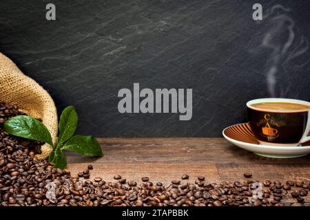 Kaffee Komposition mit Kaffeetasse, Kaffeebohnen in Kaffeesack, und Kaffeeblätter auf einem Holztisch, mit Raum für Text zum Beschriften Foto Stock