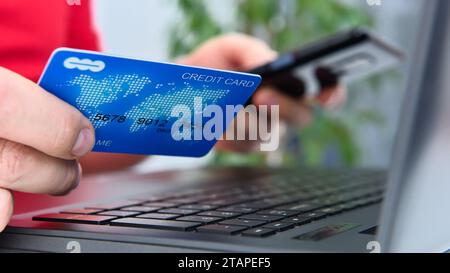 Uomo che usa uno smartphone e tiene in mano la carta di credito. Concetto di pagamento e shopping online. Primo piano Foto Stock