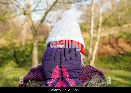 Ritratto di una donna matura che si nasconde dietro guanti invernali e due berretti in inverno. Concetto di disintossicazione mentale Foto Stock