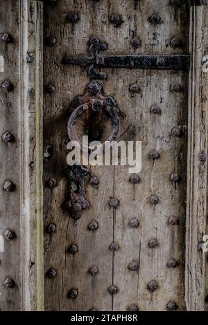 Porta medievale con borchie, legno intemperiato, maniglia per porta arrugginita, serratura e cerniera Foto Stock