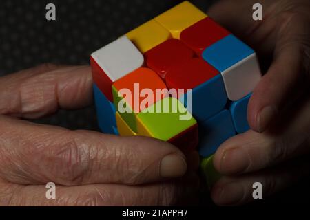 Le mani di Senior che esercitano la mobilità delle dita con un cubo di rubik Foto Stock
