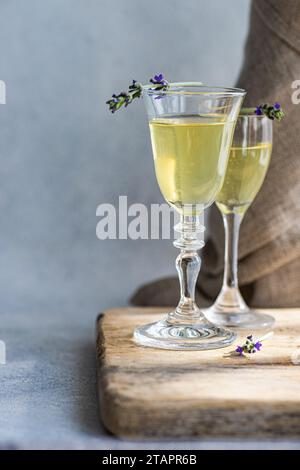 Bicchieri con bevanda Limoncello e fiori di lavanda sul tavolo in pietra nelle giornate di sole Foto Stock