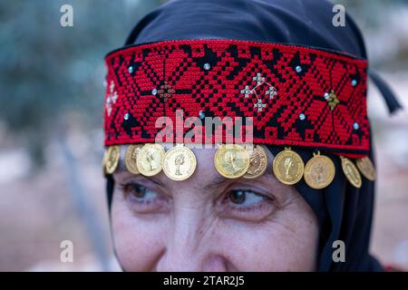 Un copricapo da donna palestinese in rosso e nero con accessori dorati Foto Stock