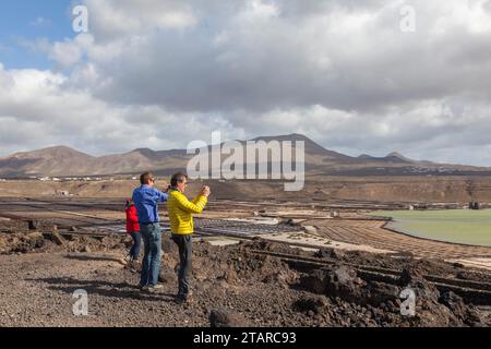 Turisti che fotografano le saline di Janubio, Salinas de Janubio, la produzione di sale marino, Lanzarote, Isole Canarie, Spagna Foto Stock