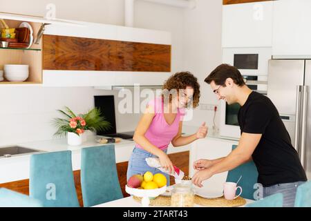Coppia adulta felice in piedi vicino al tavolo da pranzo e conversando in cucina Foto Stock
