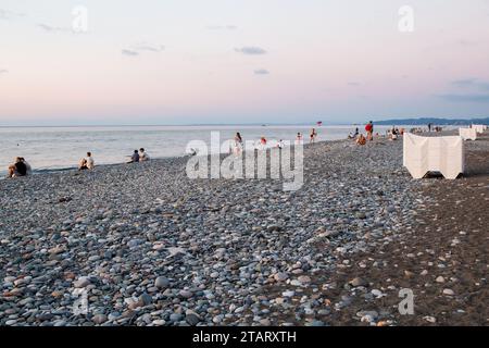 Batumi, Georgia - 19 settembre 2023: La gente guarda il tramonto sul Mar Nero sulla spiaggia di ciottoli della città di Batumi la sera d'autunno Foto Stock