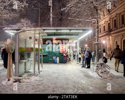 Vienna, Austria, Austria. 2 dicembre 2023. La gente aspetta il tram vicino al chiosco degli hot dog durante una forte tempesta di neve a Vienna. Le tempeste di neve attraversarono gran parte dell'Europa, causando difficoltà di viaggio e cancellazioni dei voli. (Immagine di credito: © Bianca Otero/ZUMA Press Wire) SOLO USO EDITORIALE! Non per USO commerciale! Foto Stock