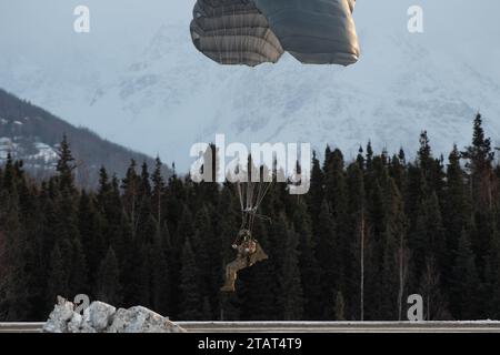 Un paracadutista dell'esercito degli Stati Uniti della 4th Quartermaster Company, 725th Brigade Support Battalion (Airborne), 2nd Infantry Brigade Combat Team (Airborne), 11th Airborne Division, discende sopra Malemute Drop zone durante l'addestramento militare in caduta libera presso Joint base Elmendorf-Richardson, Alaska, 30 novembre 2023. Air Force Special Warfare Airmen, Alaska Air National Guard aviatori e paracadutisti dell'esercito hanno condotto l'addestramento congiunto di supporto aereo per garantire la prontezza della missione in un ambiente artico. (Foto dell'aeronautica militare statunitense di Raina Dale) Foto Stock