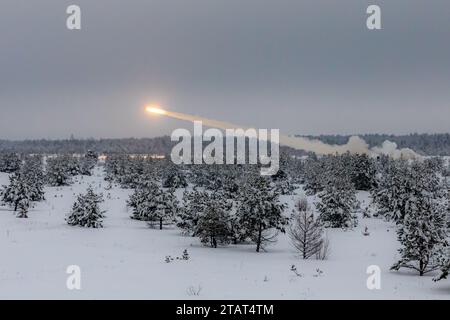 Soldati dell'esercito degli Stati Uniti assegnati alla 3rd Infantry Division Artillery e al 3rd Battalion, 27th Field Artillery Regiment, 18th Field Artillery Brigade, 82nd Airborne Division, dimostrano il M142 High-Mobility Artillery Rocket System (HIMARS) a soldati multinazionali del Enhanced Forward Presence Battle Group Lettonia durante un'esercitazione di fuoco vivo a Camp Adazi, Lettonia, 2 dicembre 2023. Durante l'esercitazione, HIMARS volò in un aeroporto vicino e iniziò rapidamente la sua missione di fuoco vivo, mostrando la sua mobilità e le sue capacità di infiltrazione rapida e migliorando l'interoperabilità tra gli Alleati della NATO. Il terzo Foto Stock