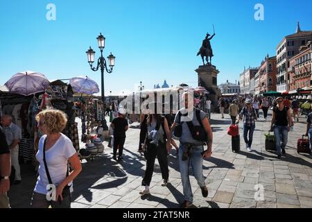 Il turista passeggia accanto alle bancarelle di souvenir sulla Riva degli Schiavoni, vicino a San Marco-San Zaccaria, alla luce del sole del pomeriggio Foto Stock