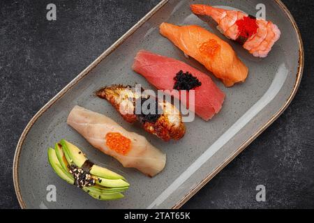 Sushi Nigiri assortito su un piatto, su cemento scuro Foto Stock