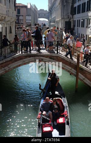 Venezia, Italia, turisti su ogni ponte sul rio dei Greci con vista sul Ponte dei Sospiri, un giro di coppia in gondola sul canale Foto Stock