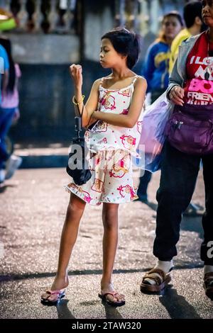 Una giovane e graziosa ragazza filippina aspetta la sua famiglia fuori dalla chiesa di Santo Nino de tondo a Manila, nelle Filippine. Foto Stock