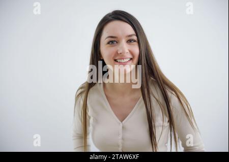 Il sorriso sincero della giovane donna europea, la gioia della risata Ucraina, scintilla negli occhi su uno sfondo bianco, una ragazza carina con i capelli lunghi Foto Stock