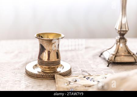 Tradizionale tazza per bambini ebraica decorativa. Tazza d'argento con piattino riempita fino all'orlo di vino viola isolato su fondo bianco Foto Stock