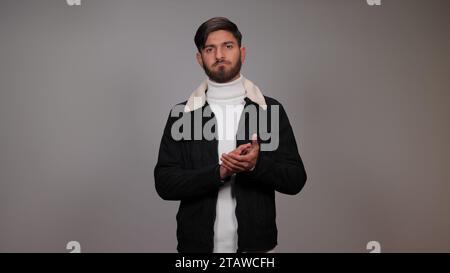 Un giovane che batte le mani su uno sfondo grigio. Foto Stock