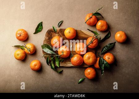 Arance mandarine, clementine o mandarini con foglie su sfondo scuro, vista dall'alto Foto Stock