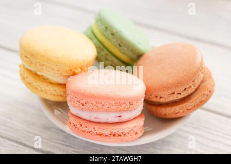 Il set di quattro Macaron aromatizzati. Le torte colorate sullo sfondo del tavolo di legno bianco. Vista ravvicinata. Foto Stock