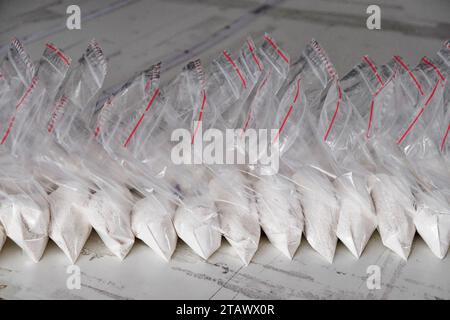 Un gran numero di bustine trasparenti riempite di polvere bianca. Polvere bianca confezionata in bustine piccole. Foto Stock