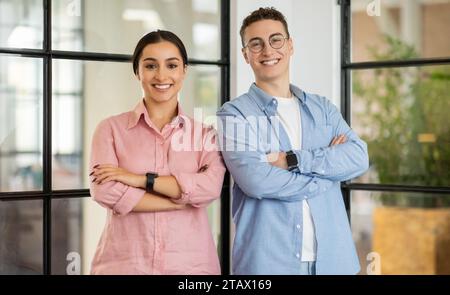 Felice fiduciosa donna millenaria del Medio Oriente e caucasica in casual con le braccia incrociate Foto Stock