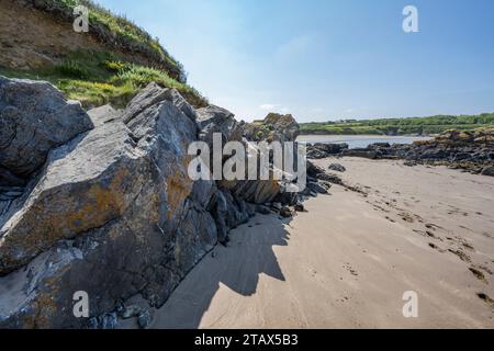 Impronte sulla sabbia accanto alla formazione rocciosa sul bordo della spiaggia di Angle Bay Foto Stock