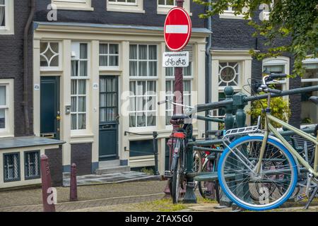 Paesi Bassi. Argine del canale estivo di Amsterdam con case tradizionali e biciclette parcheggiate. Sotto il cartello di divieto c'è un'iscrizione in Dutc Foto Stock