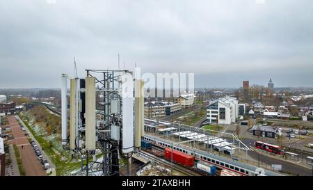 OLDENZAAL, PAESI BASSI - 2 DICEMBRE 2023: Torre di comunicazione telefonica mobil sopra il villaggio e la stazione ferroviaria locale. Foto Stock