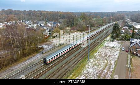 OLDENZAAL, PAESI BASSI - 2 DICEMBRE 2023: Vista aerea di una locomotiva delle Ferrovie olandesi (NS) di fronte ad alcuni vagoni passeggeri delle Ferrovie tedesche (DB). Foto Stock