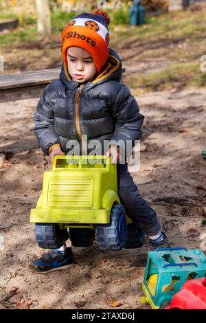 Ragazzi che giocano con i giocattoli nel box di sabbia del parco giochi Foto Stock